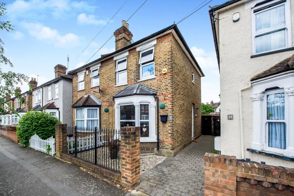 A bay-fronted brick semi-detached house on Cotleigh Road, set behind black railings and a block-paved forecourt, with neighbouring houses running down the street beyond it